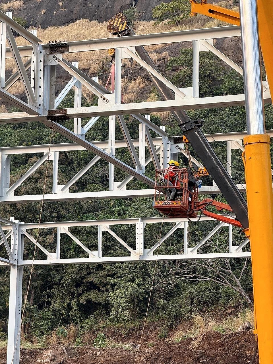 Erector working from a boom lift platform at roof truss level, Hyundai plant structure, Pune