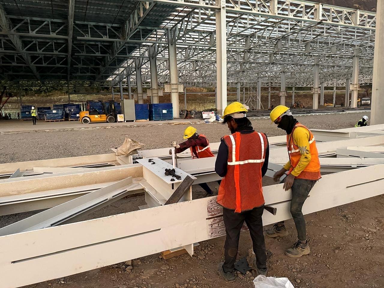 Fabricators in helmets and vests preparing steel members on site, Hyundai plant structure, Pune