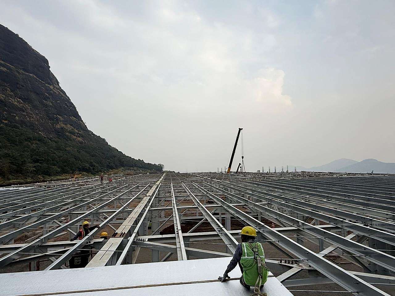 Roof steelwork stretching across the Hyundai car plant in Pune, with the hills beyond